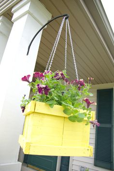 a yellow hanging planter filled with purple flowers