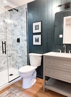 a white toilet sitting in a bathroom next to a walk in shower under a mirror