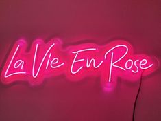 a neon sign with the word la vie en rose written in pink on a wall