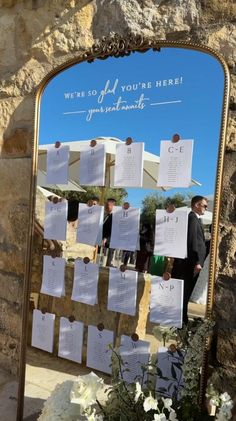 a mirror that has been decorated with notes attached to the wall and flowers in front of it