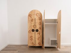 a wooden cabinet sitting in the middle of a room with two doors open to reveal another door