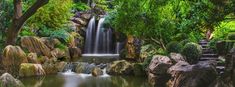 there is a waterfall in the middle of some rocks and trees with water running down it