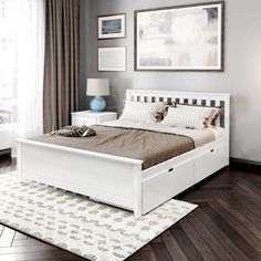 a white bed sitting on top of a hard wood floor next to a window with curtains