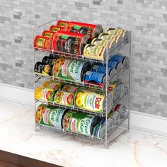 a metal spice rack holding canned food on top of a white counter next to a gray tiled wall