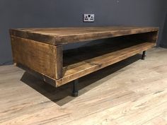 a wooden table sitting on top of a hard wood floor next to a gray wall