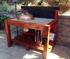 an outdoor bbq grill with pots and pans on the burner, next to a brick wall