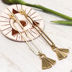 This pair of long, minimal, brass post earrings are beautifully golden with a perfect sway. The brass oval is hand brushed to a golden shine and then waxed to slow tarnish. The trio of triangle charms on these earrings are solid brass adding just the right amount of weight to encourage a bit of sway. The triangles are brought to a golden polish and waxed. Brass ball post or brass hook attachment available. Both nickel free. Everyday Long Drop Brass Linear Earrings, Minimalist Brass Linear Earrings With Long Drop, Minimalist Brass Linear Long Drop Earrings, Modern Brass Dangle Linear Earrings, Gold-tone Dangle Linear Earrings In Brass, Minimalist Gold Linear Brass Earrings, Brass Hook, Triangles, Post Earrings