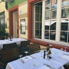 an outdoor dining area with tables, chairs and bottles of wine on the windowsill