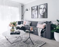 a living room with grey couches and pink pillows on top of the rugs