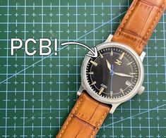 a watch sitting on top of a piece of paper with the words pcb below it