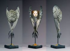 three different angles of a sculpture with wings on it's head and body, each holding an object in the other hand