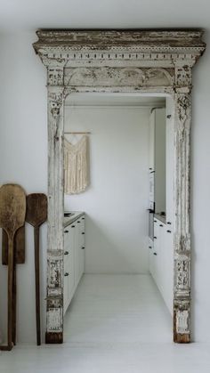 an old mirror in the middle of a kitchen with wooden utensils on the floor