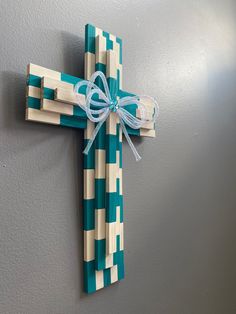 a cross made out of wood with a bow on the front and back ends, hanging on a wall