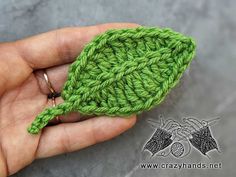 a hand holding a green crocheted object in it's palm