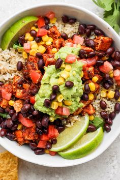 a bowl filled with black beans, rice and guacamole next to tortilla chips