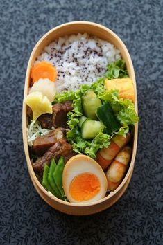 a bowl filled with rice, meat and veggies on top of a table