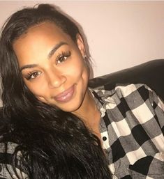 a woman sitting on top of a couch smiling at the camera with long black hair