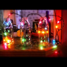 three glass bottles with lights in them sitting on a table