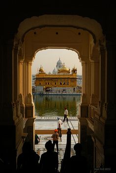 people are standing in an archway looking at the water and golden building behind them,