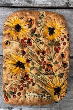 a pizza with sunflowers and cherries on it sitting on top of a wooden table