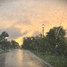 rain drops on the windshield of a car as it sits in front of a street light