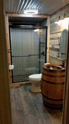 a bathroom with a wooden barrel next to a toilet and shower stall in the corner