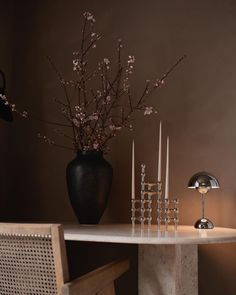 a table topped with a vase filled with flowers next to candles and a lamp on top of it