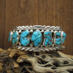 Handsome handmade sterling silver and turquoise cuff bracelet.  The cuff is 6 3/4" long including the 1 1/4" opening. There are nine turquoise nugget stones set across the front. The tallest is 21mm tall. They taper to 13mm in the back. A silver bead is between each stone at the top and bottom. Twisted silver wire rope and a nicely cut border finish the bracelet. It is stamped T Sterling inside. This bold-looking bracelet is in good condition. Thank you for looking. Please let us know if you hav Southwestern Aesthetic, Butterfly Headpiece, Vintage Turquoise Jewelry, Turquoise Jewelry Necklace, Turquoise Stone Jewelry, Turquoise Belt, Silver Smithing, Turquoise Jewellery, Turquoise Jewelry Native American