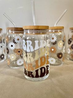 four glass jars with straws in them sitting on a table