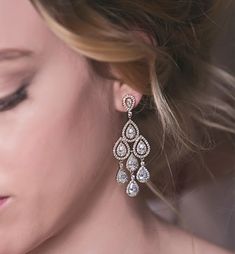 a close up of a woman's face wearing earrings with tear drops on them