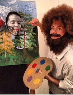 a man with an afro wig and beard holding a paint palette in front of his face