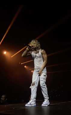 a man standing on top of a stage with his hand up to his face while holding a microphone