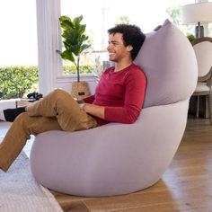 a man sitting on a bean bag chair in the middle of a living room smiling