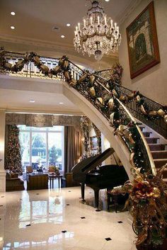 a grand piano sitting under a chandelier in a living room next to a staircase