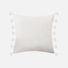 a white pillow with pom - poms on the front and back of it