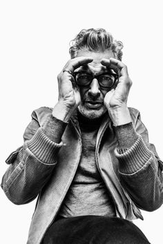 a black and white photo of a man holding his hands up to his face while sitting down