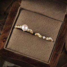 a pair of pearl and gold earrings in a box on top of a wooden table