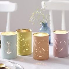 four different colored canisters sitting on top of a table next to a vase