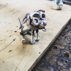 a metal dog sculpture sitting on top of a wooden table next to screws and nuts