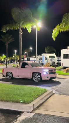 a pink truck is parked in front of some palm trees and rv parks at night