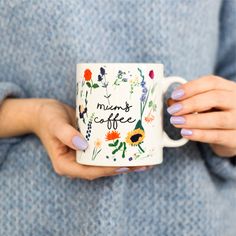 a woman holding a coffee mug with flowers on it