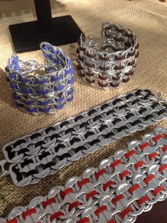 four pieces of silver and red bracelets sitting on top of a table next to each other