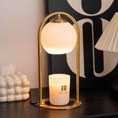 a white candle sitting on top of a table next to a lamp