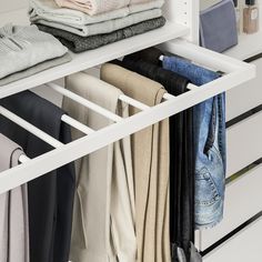 an organized closet with clothes hanging on the rails and folded jeans in front of it