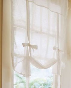 a window with white sheer curtains hanging from it's side