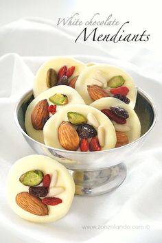 white chocolate with nuts and pistachios in a silver bowl on a white cloth