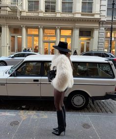 a woman standing in front of a white car