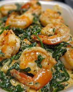 a white bowl filled with shrimp and spinach