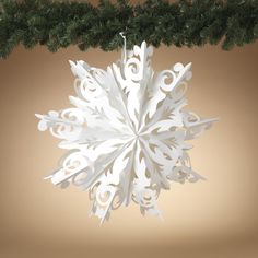 a snowflake ornament hanging on a christmas tree branch with brown background