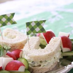 a plate topped with sandwiches and cucumbers on top of a green table cloth